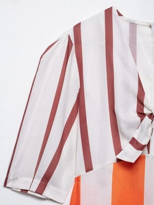 Macro detail of V-neckline with drawstring knot and colorful vertical striped woven fabric
