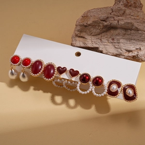 Detail of vintage earring set with red resin hearts and faux pearls on display card