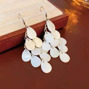Macro shot of tiered white teardrop shell fringe earrings with silver metal hooks