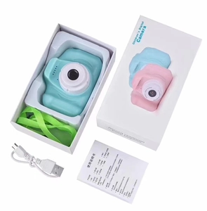 Unboxing detail showing kids digital camera with green lanyard and USB charging cable