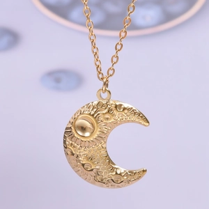 Macro shot of gold crescent moon pendant featuring artistic lunar crater textures on O-chain