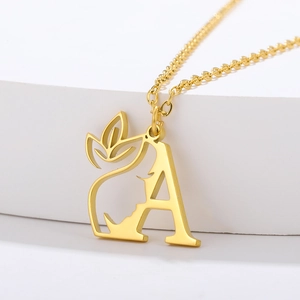 Macro shot of gold letter A pendant with hollow face silhouette and leaf detail