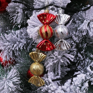 Three assorted colorful candy Christmas ornaments hanging on a snowy tree branch
