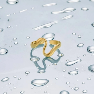 Elegant gold-tone irregular wavy snake-shaped adjustable ring on a wet reflective surface