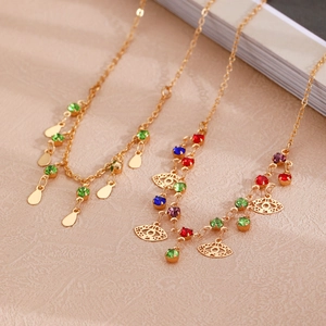 Detail of layered gold necklaces featuring evil eye pendants and colored crystals