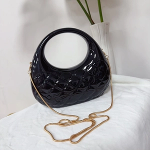 Détail du sac coquille noir brillant avec motif à losanges et chaîne dorée fine