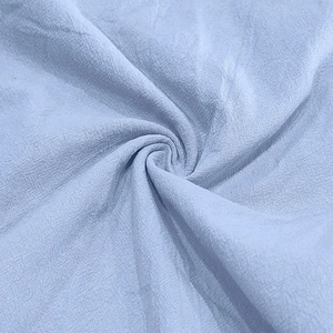 Macro detail of light blue linen fabric texture showing breathable weave and soft drape