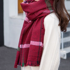 Detail of red houndstooth knit scarf with colorful stripes and soft fringe edges