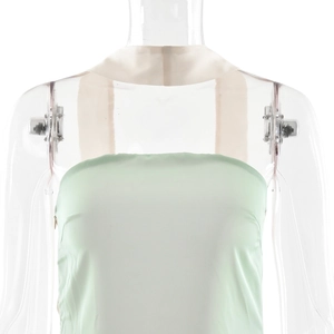 Détail d'une robe en satin vert clair avec de larges bretelles beige et décolleté bustier