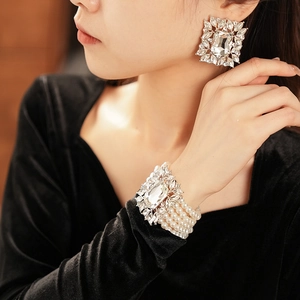 Detail of luxury square diamond earrings and matching multi-layer pearl bracelet set