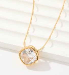 Primer plano de collar dorado con gran colgante de circón cuadrado en fondo blanco