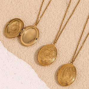 Macro view of gold plated oval locket necklaces with engraved floral daisy details