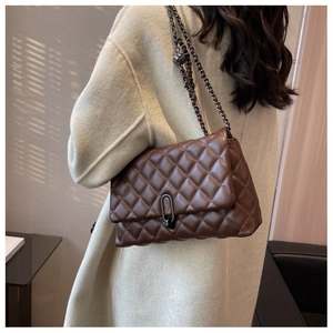 Brown quilted leather chain bag worn over a beige coat by a model from a side profile