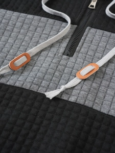 Macro shot of grey-black quilted hoodie with metal zipper and leather drawstring detail