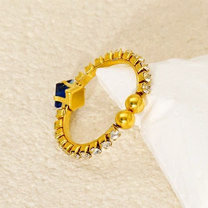 Detail of a vintage gold ring with blue square zircon and spherical metal accents