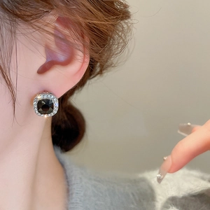 Detailed close-up of a geometric square earring with black stone and diamond halo inlay
