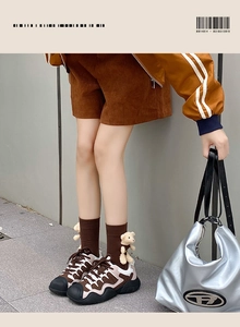Close-up of brown crew socks featuring a 3D plush bear ornament and platform sneakers