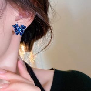 Close-up of blue zircon butterfly earrings worn on ear with elegant metallic finish