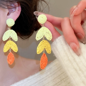 Detail of bohemian raffia tassel earrings with green, yellow, and orange gradients