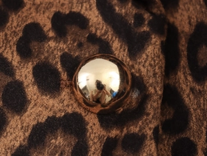 Macro view of leopard print suede fabric with a reflective gold button detail
