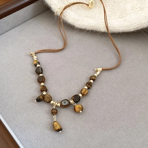 Detailed shot of tiger eye stone necklace with leather cord on gray velvet jewelry tray