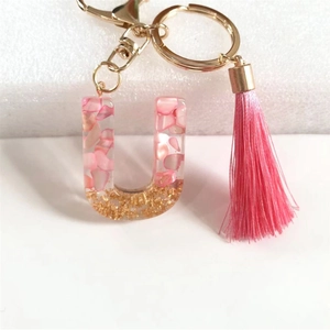 Macro view of pink tassel keychain with resin letter U containing gold foil and shells