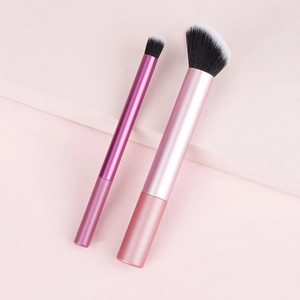 Detail of soft makeup brushes with rose gold handles on a pink geometric platform