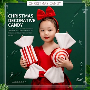 Red and white striped Christmas candy hanging ornaments held by a girl in red dress