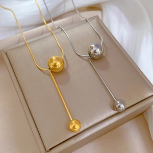 Minimalist titanium steel necklaces with gold ball and bar pendants on silk cloth