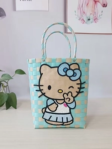 Detail of hand-woven bucket bag featuring Hello Kitty embroidery in mint green and beige