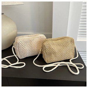 Detail of hand-woven straw crossbody bags showing texture and zipper closure