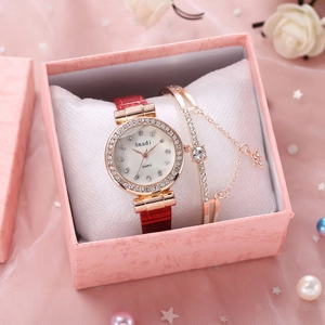Détail d'un coffret montre et bracelet en or rose avec bracelet en cuir rouge élégant