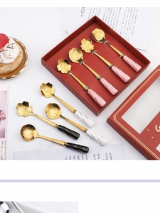 Close-up of gold-plated floral dessert spoons with rose and sakura motifs in a gift box