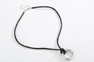 Detail of black velvet rope necklace featuring a minimalist silver circular pendant