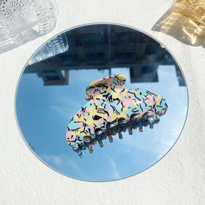 Artistic splash pattern acetate hair claw clip reflected on a circular mirror