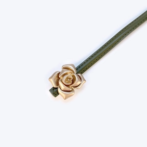 Detailed close-up of army green leather belt featuring a 3D golden flower metal buckle