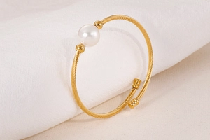 Vue détaillée d'un bracelet torsadé doré orné d'une grande perle blanche élégante