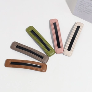 Detailed view of leather hair clips in brown, grey, green, pink and beige tones
