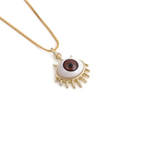 Macro shot of gold evil eye pendant necklace with fine eyelashes and brown eye detail