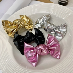 Close-up of metallic leather bow hair clips in gold, silver, black and pink colors