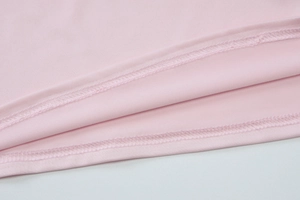 Gros plan de l'ourlet du gilet rose montrant la double couture et la texture du tissu