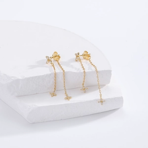 Detailed macro view of gold s925 silver floral tassel earrings on a white plaster base