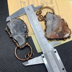 Detail van onregelmatige agaat hangers met bronzen randen gemeten door een schuifmaat