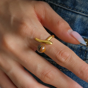 Detailed close-up of a double-layer tiger eye stone open ring in gold on a finger