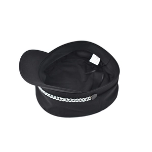 Detail view of a black newsboy hat with silver chain decoration and brand washing label
