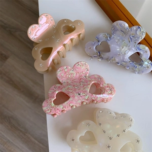 Detailed view of acetate hair claws in heart and cloud shapes with sparkling rhinestones