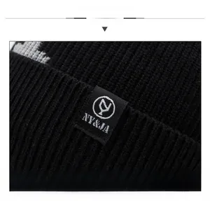 Nahaufnahme der schwarzen Strickmütze mit Textil-Patch und präziser Rippenstrick-Struktur