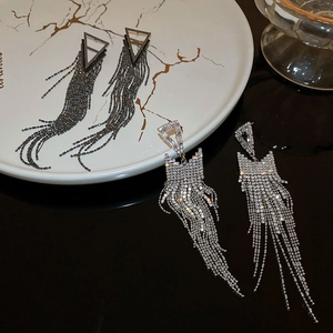 Detail of luxury triangle fringe earrings with shimmering silver crystals on marble