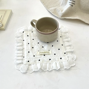 Close-up of white heart pattern fabric coaster with delicate lace edges and cup