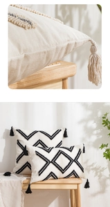 Detail of beige tufted throw pillow with black geometric embroidery and tassel accents